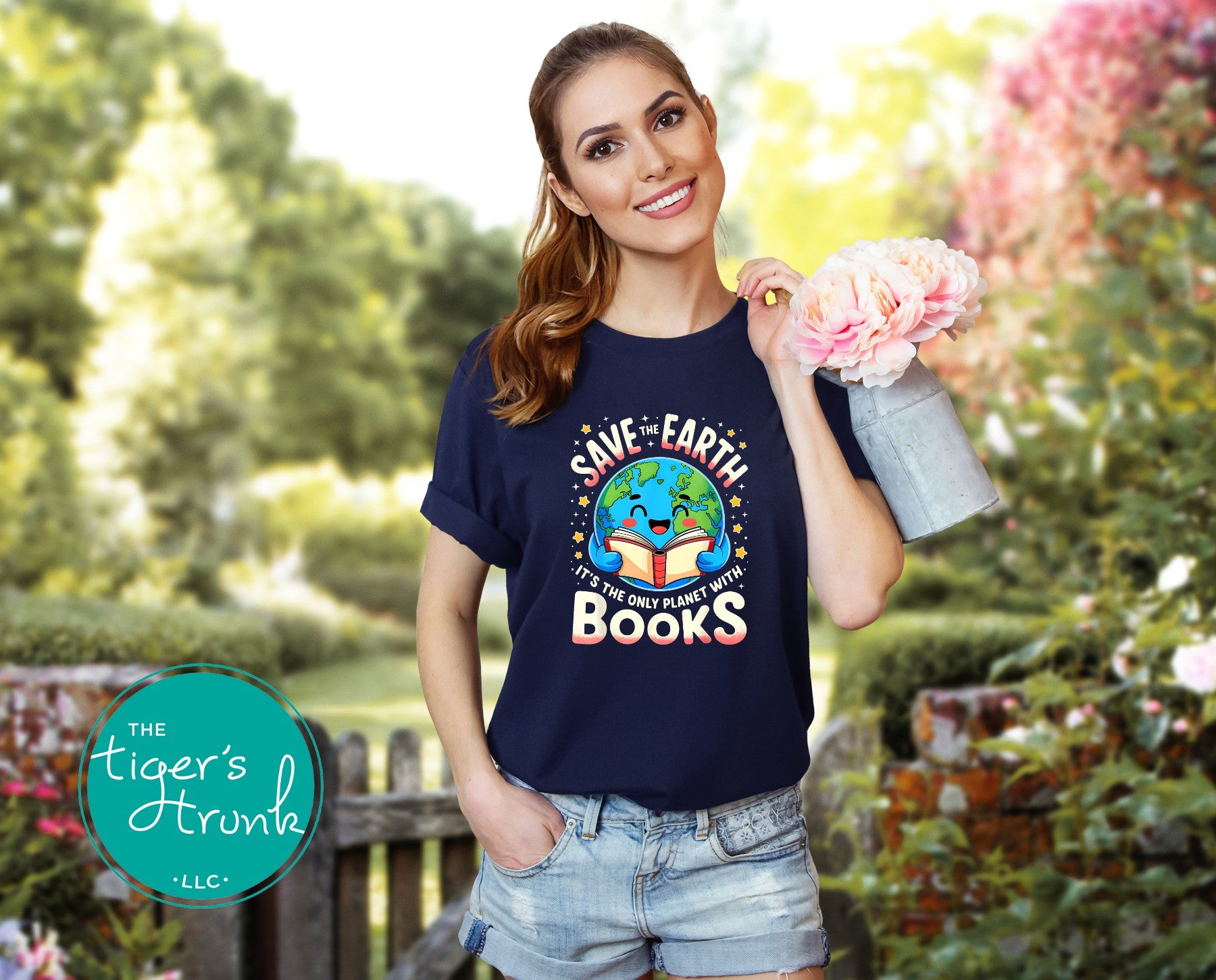 Woman wearing a navy blue t-shirt with an environmental message, holding flowers in a garden.