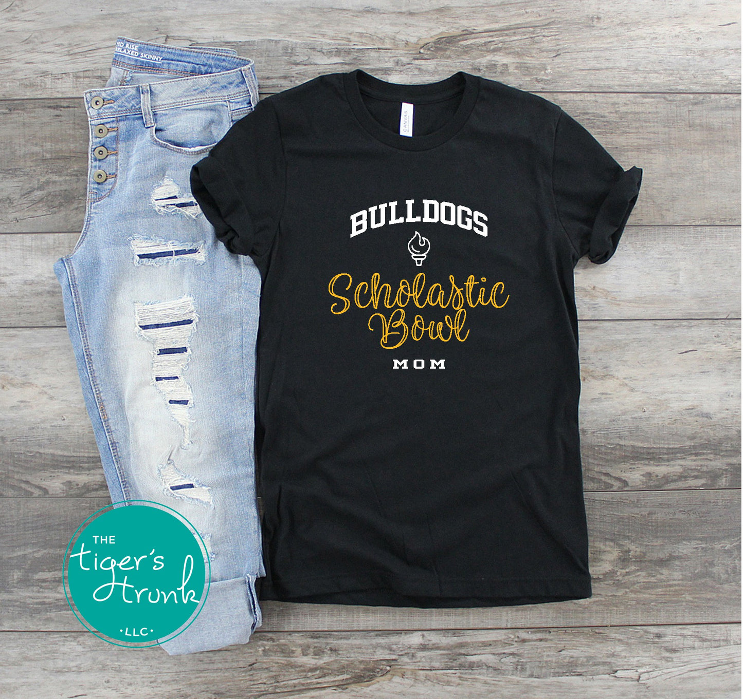 Black t-shirt with 'Bulldogs Scholastic Bowl Mom' text on a wooden surface with jeans.