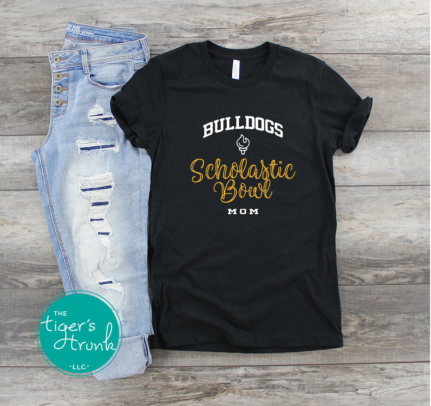 Black t-shirt with 'Bulldogs Scholastic Bowl Mom' text on a wooden surface with jeans.