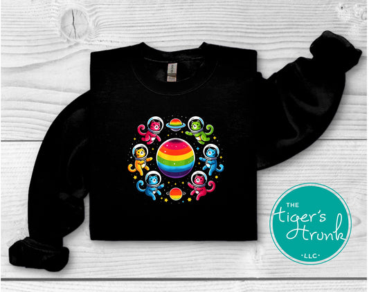 Sweatshirt with cats in space suits flying around a rainbow-colored planet, fun LGBTQ+ Pride graphic for cozy celebration and cat lovers