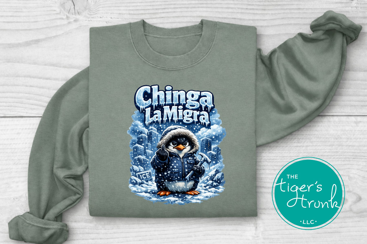 Green sweatshirt with a penguin graphic and 'Chinga La Migra' text on a white background
