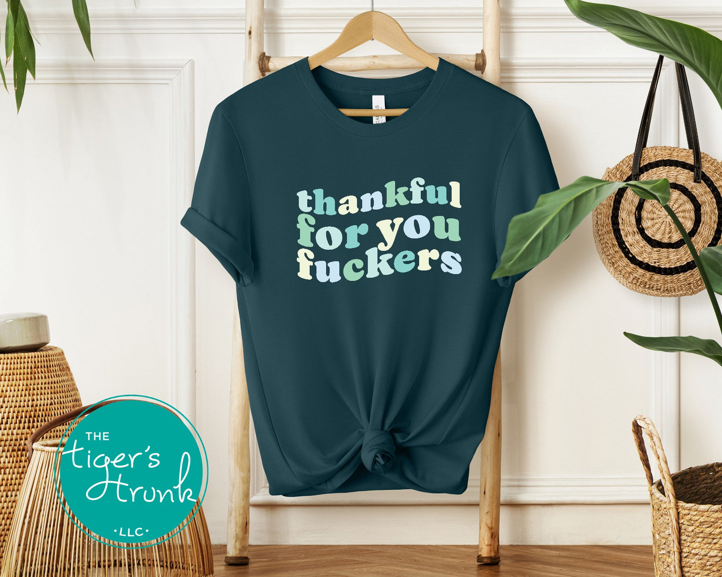 Blue t-shirt with colorful text on a hanger against a white wall with decorative elements.