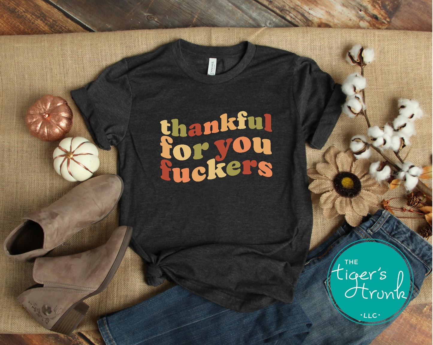 Black t-shirt with colorful text on a rustic background with boots and flowers.