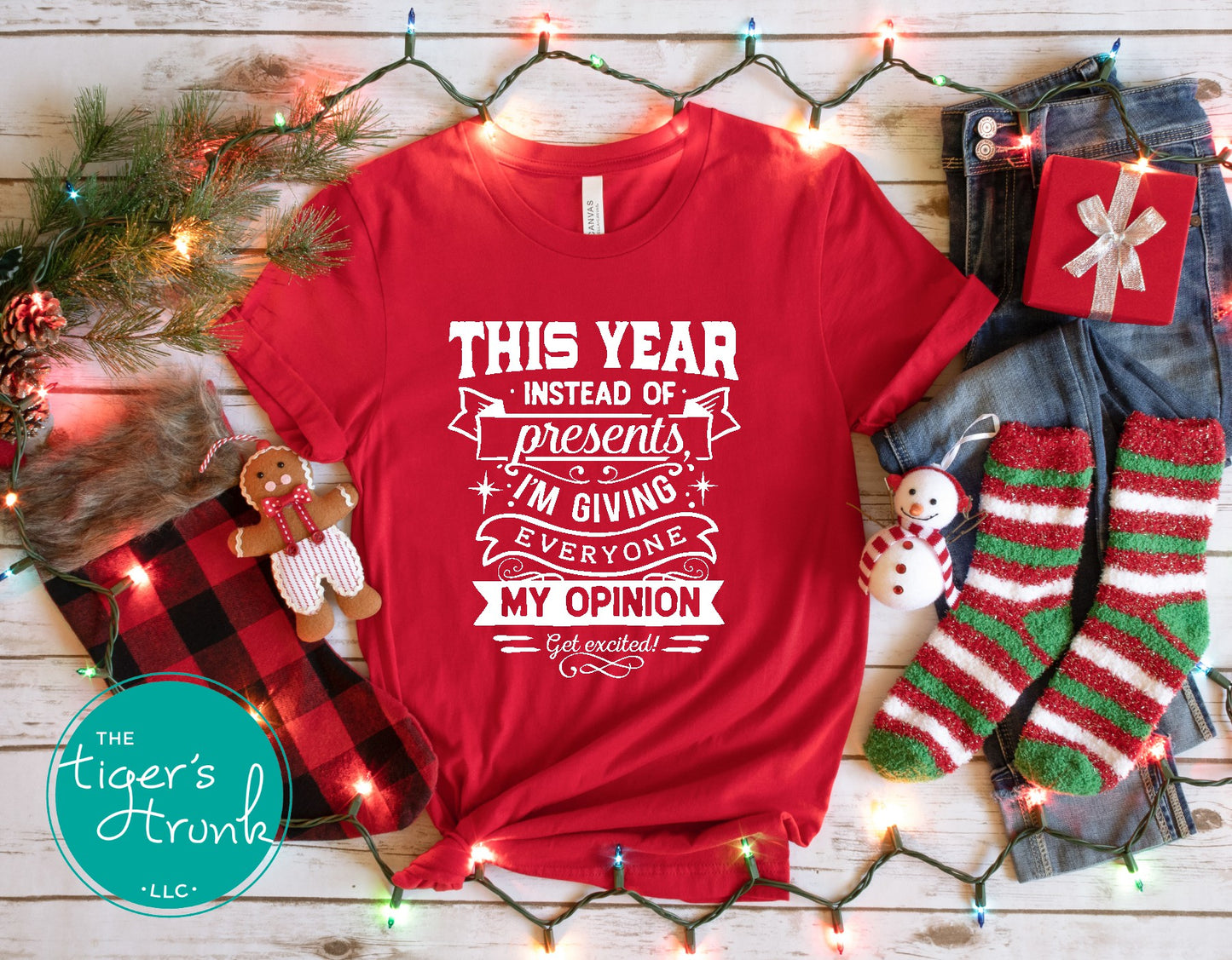 Red t-shirt with humorous text on a wooden surface with festive decorations.