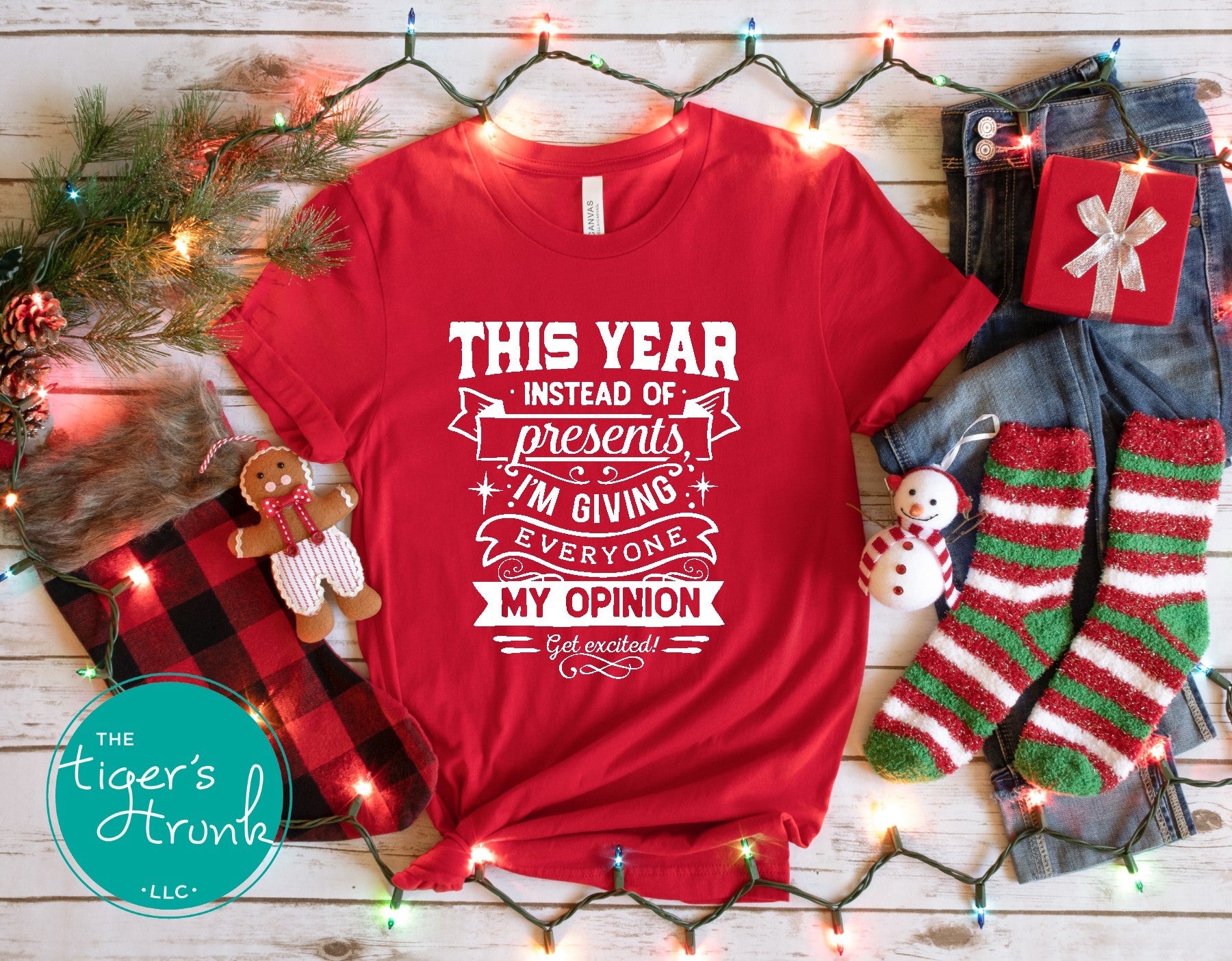 Red t-shirt with humorous text on a wooden surface with festive decorations.