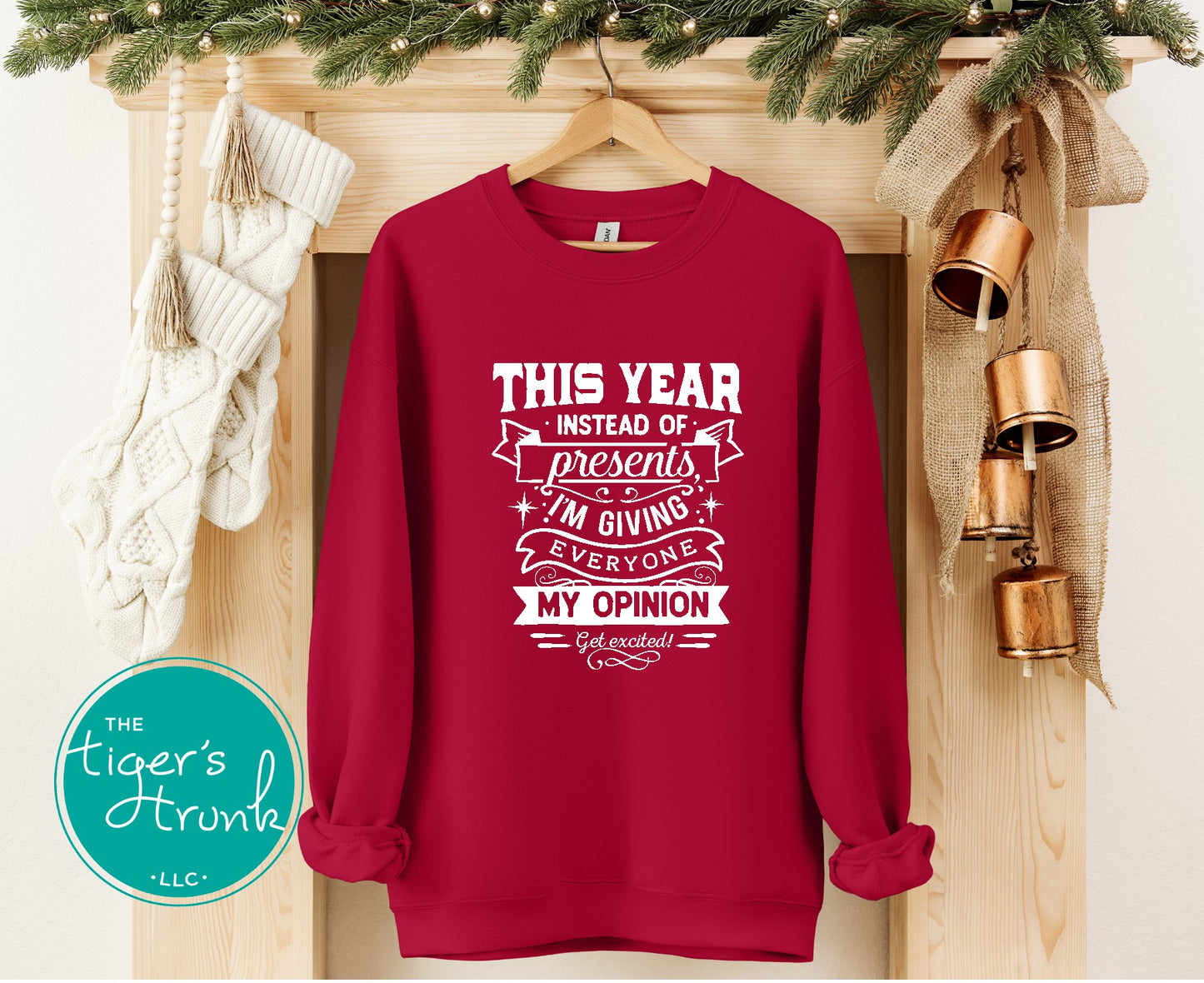 Red sweatshirt with humorous text design on a wooden surface with Christmas decorations.