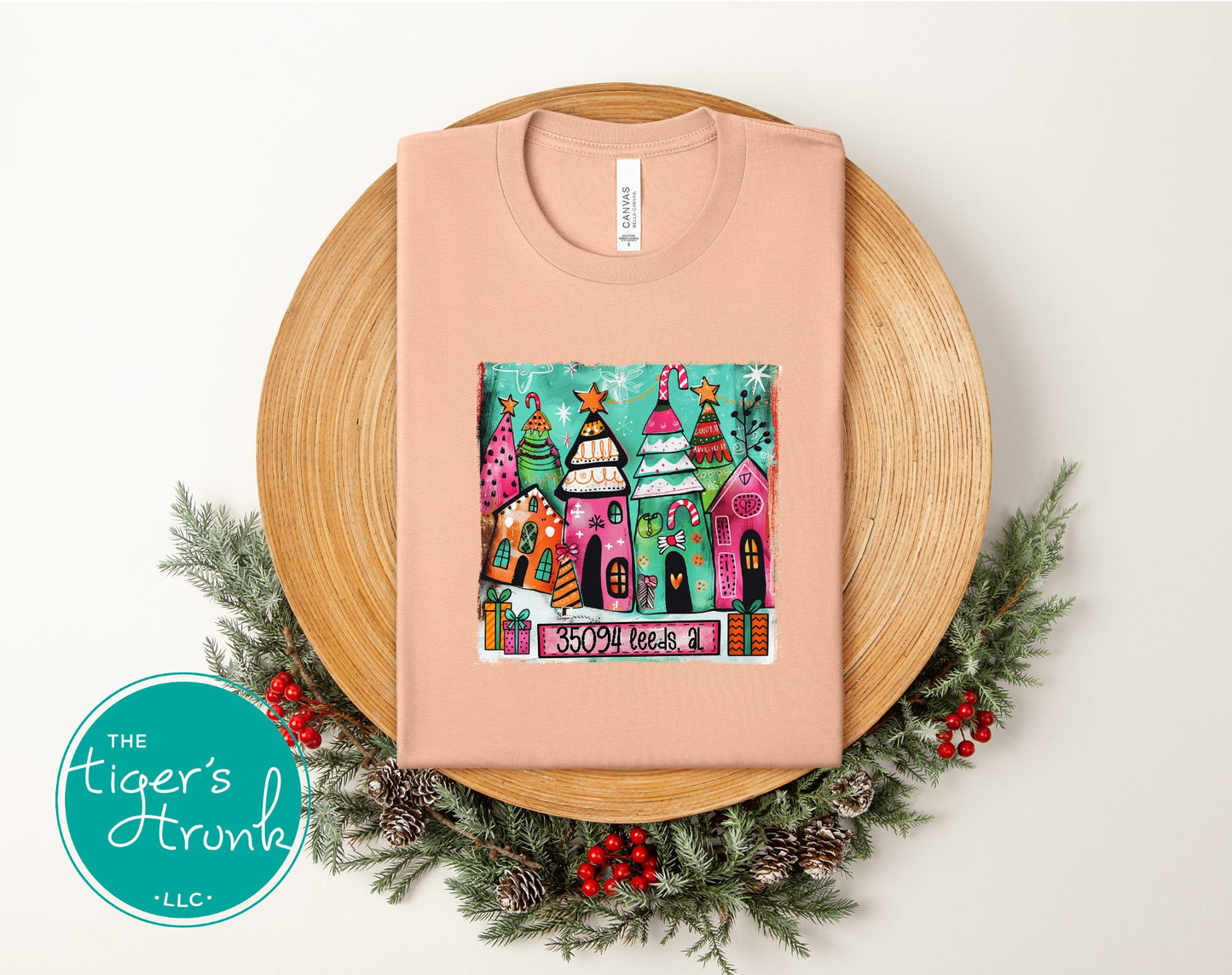 Peach Christmas shirt with vibrant whimsical holiday houses and trees personalized with ZIP code 35094 Leeds, AL.