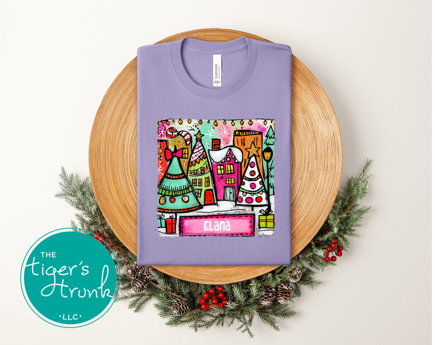 Purple t-shirt with colorful graphic design on a wooden board with Christmas decorations