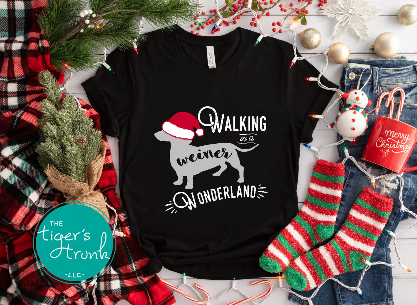 Black t-shirt with Christmas-themed design surrounded by festive items like stockings and lights.