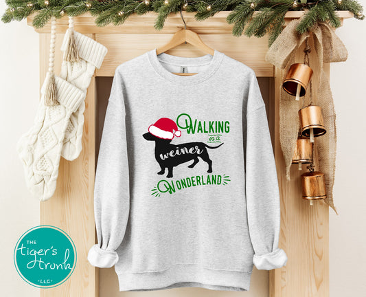 Gray sweatshirt with Christmas-themed design on a wooden surface with festive decorations.