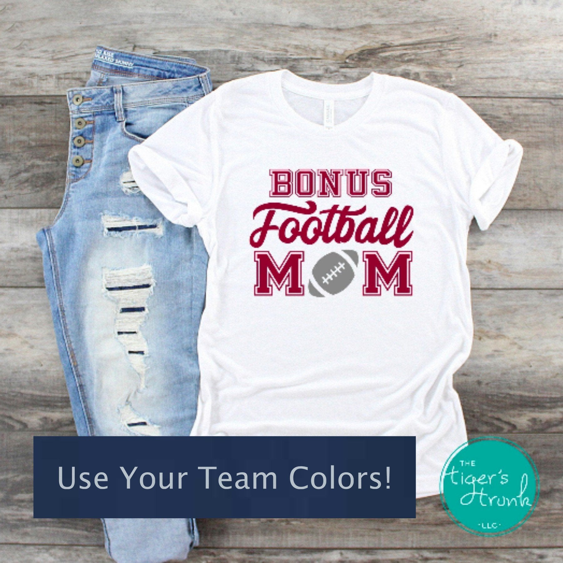 White Bonus Football Mom shirt with customizable team colors shown with distressed jeans on a wood background.